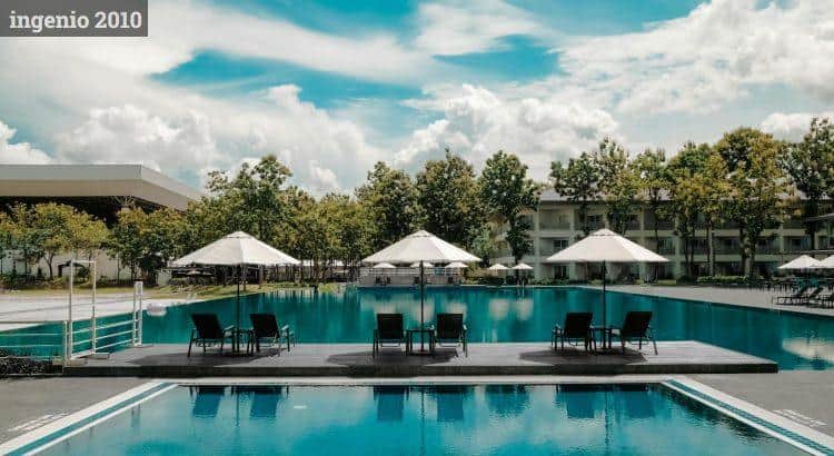 Black Outdoor Lounge Chair in Between Blue Swimming Pool Under White Cloudy Blue Sky